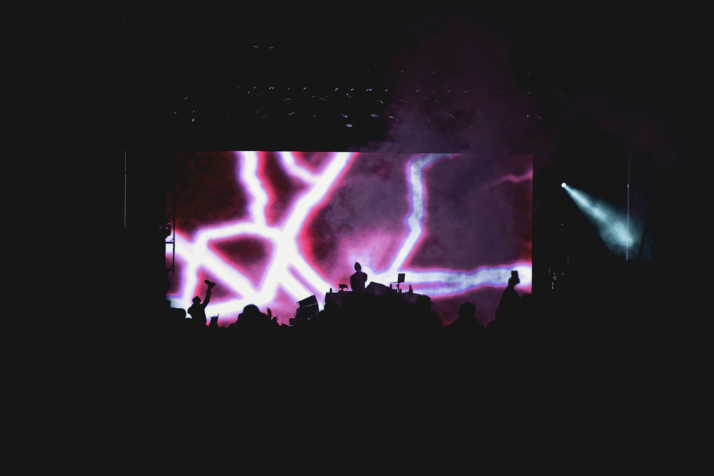 A DJ performs on stage before a large, glowing light display.