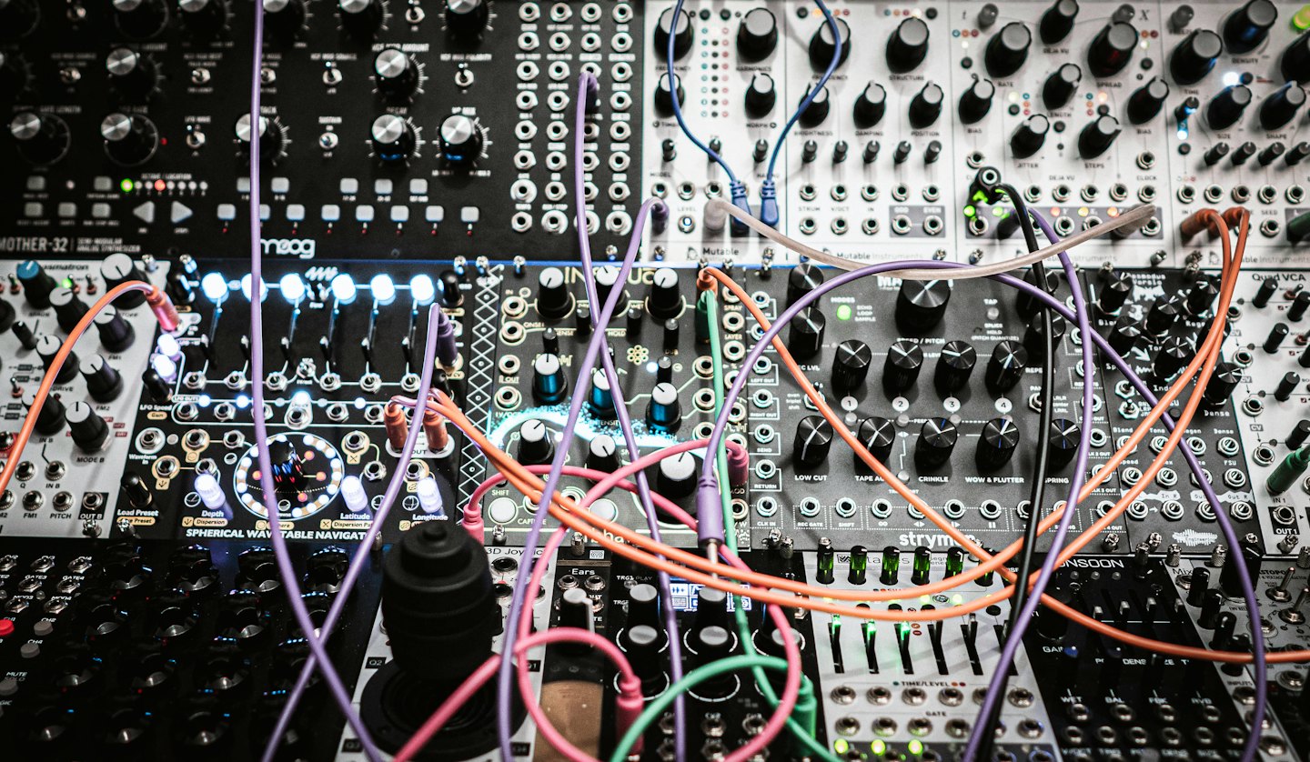 Modular synthesizer with colorful patch cables connecting black and grey modules.