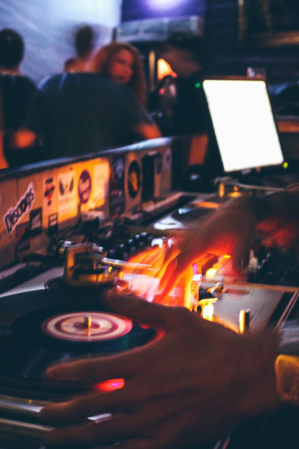 DJ's hands mixing music on turntables in a club.