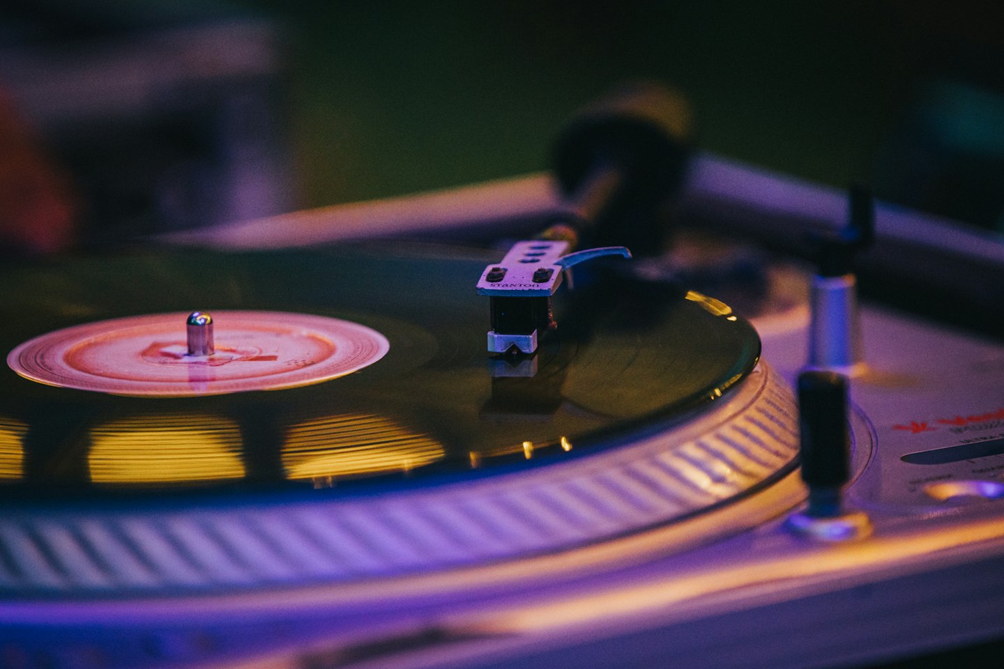 Black vinyl record spinning on a turntable with stylus.